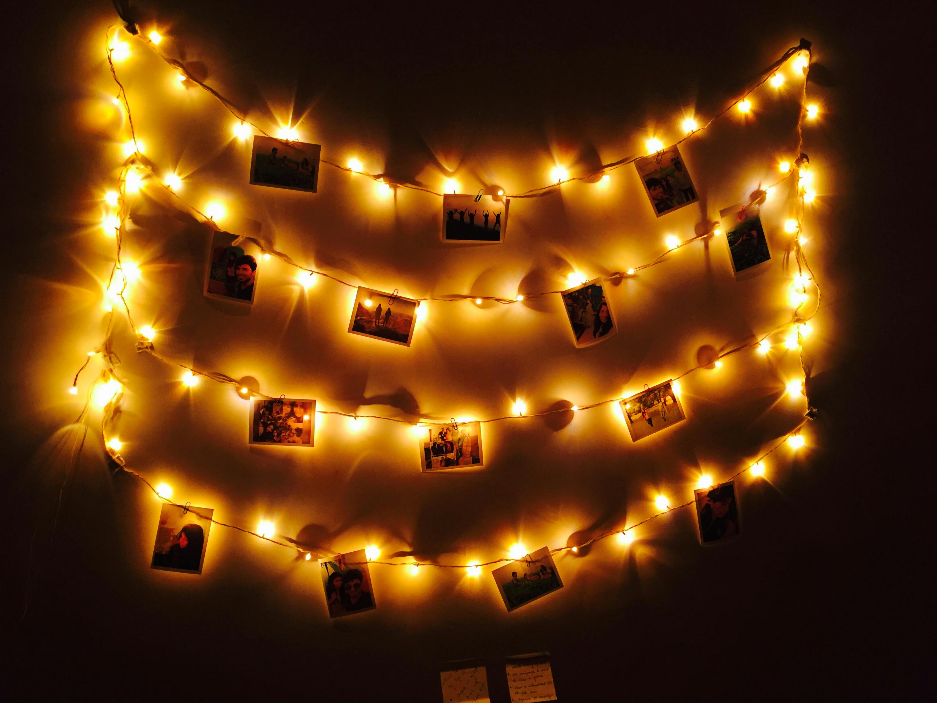 Cozy arrangement of fairy lights displaying photographs in a dark room setting.